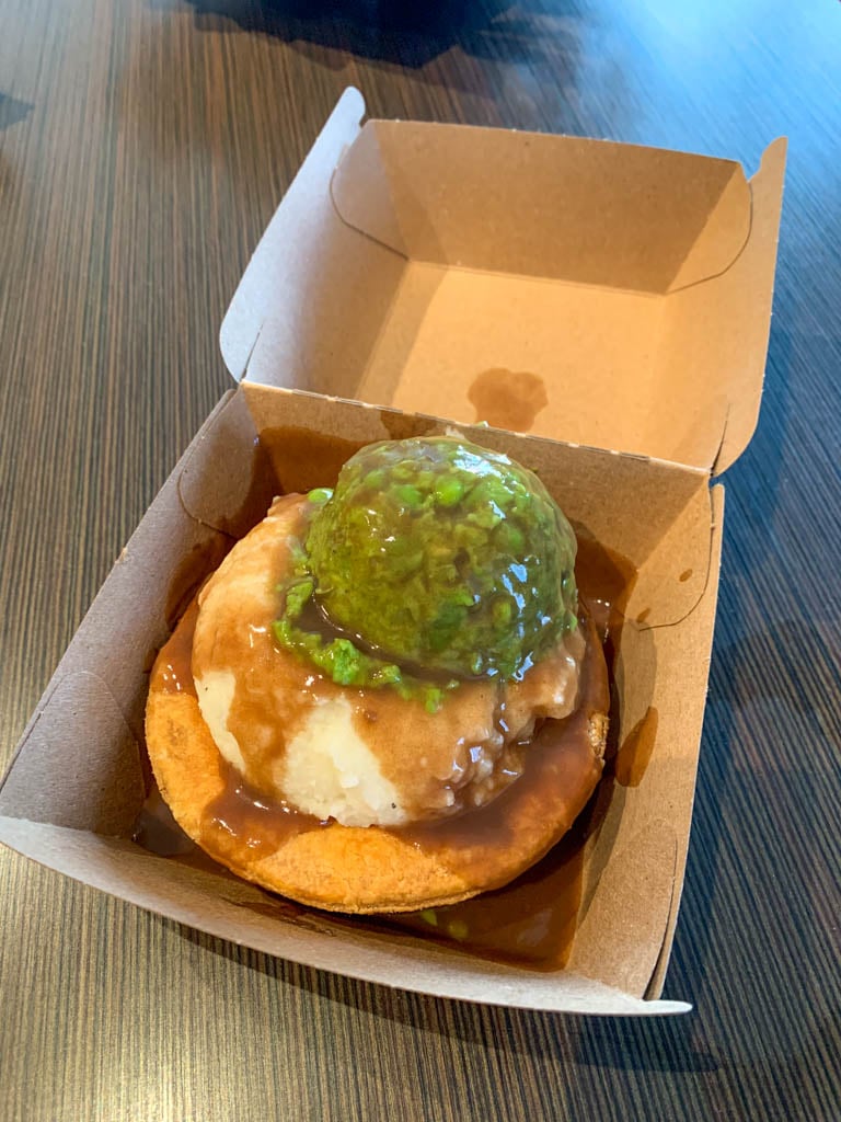 Close up of an Aussie meat pie topped with mashed potatoes, mushy peas, and gravy from Peaked Pies in Whistler