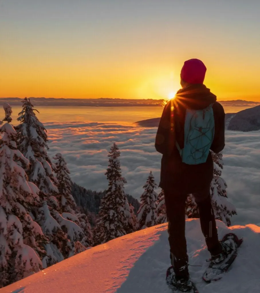 A snowshoer watches the sunset from Grouse Mountain in Vancouver