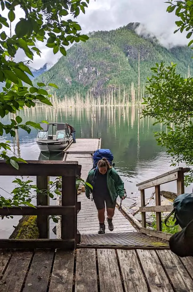 A hiker walks up the stairs from the Della Falls Trailhead dock