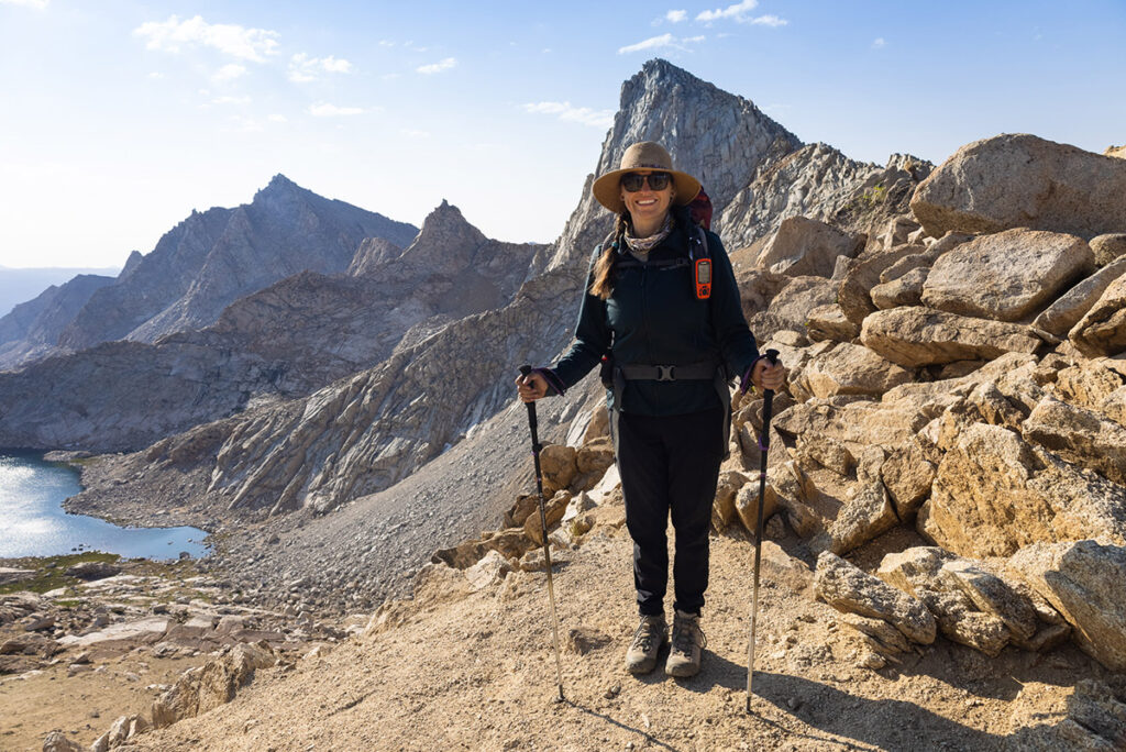 A woman wearing a hat and Mountain Hardwear Dynama2/ Ankle Pants holds trekking poles on a trail in Sequoia National Park