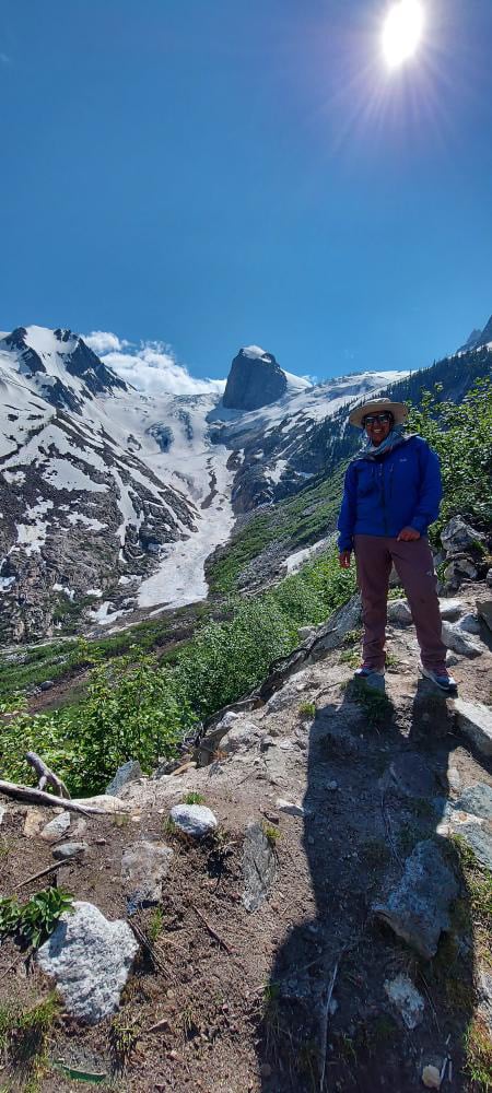 A woman wears a blue jacket and Eddie Bauer Guide Pro Pants (one of the best women's hiking pants) poses on a trail in British Columbia's Bugaboo Provincial Park