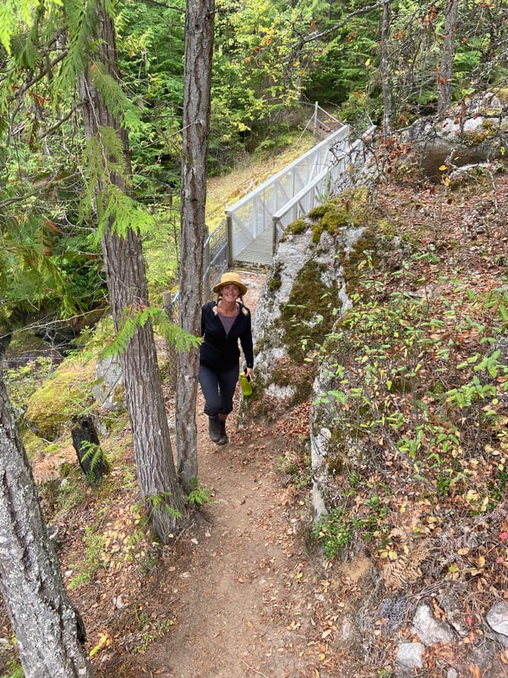 A woman hikes on a trail wearing a wide brimmed hat and Kuhl Freeflex Pants