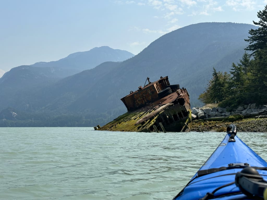 A kayaker paddlers near a shipwreck in Howe Sound