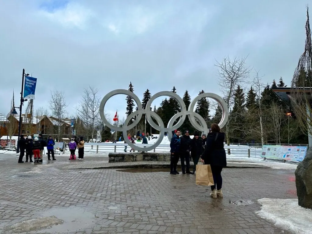 People wait in line to take photos at the Olympic rings in Whistler village in winter