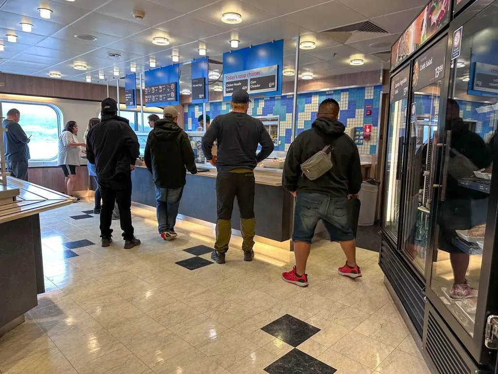 Customers wait to order food at the on-board cafeteria on the Northern Expedition ferry