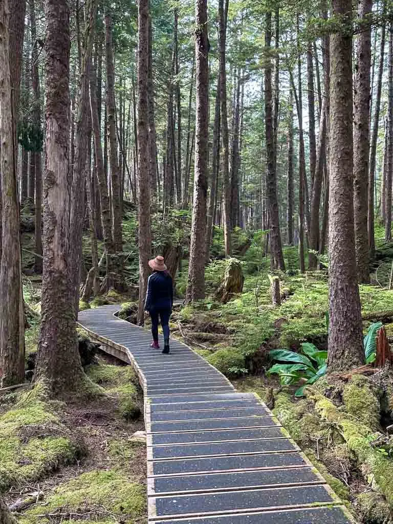 A Haida guide wearing a cedar hat leads a tour group through the forest at SGang Gwaay in Gwaii Haanas National Park Reserve