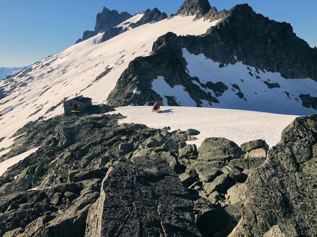 A helicopter lands next to Jim Haberl Hut in the Tantalus Mountains near Squamish