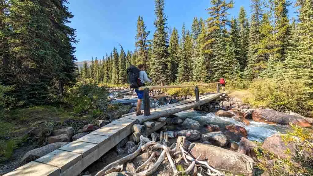 A hiker crosses the bridge over Evelyn Creek on the Skyline Trail