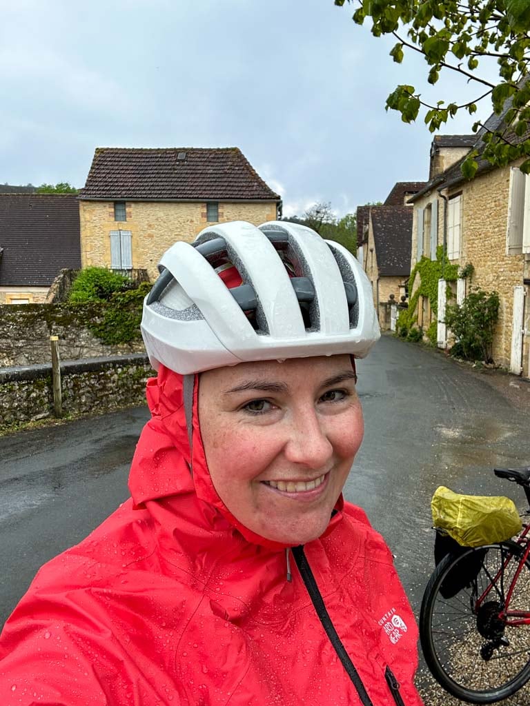 A woman wears a Mountain Hardwear Minimizer rain jacket and a bike helmet in the pouring rain. 