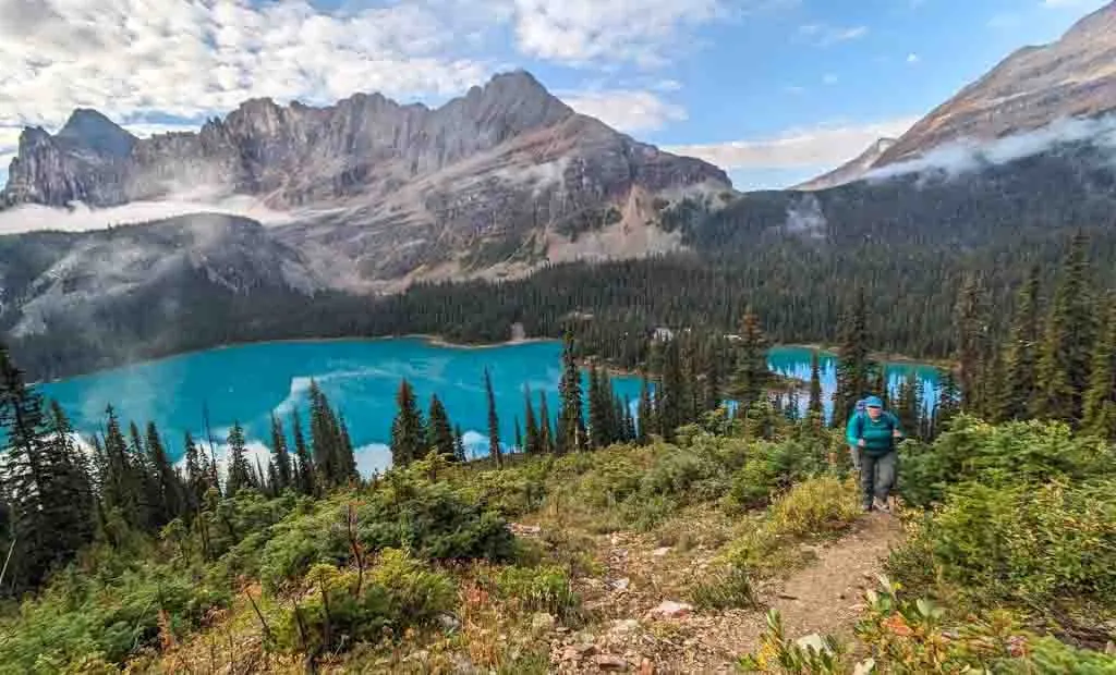 A hiker climbs up the steep trail to Wiwaxy Gap. You can see Lake O'hara far below her.