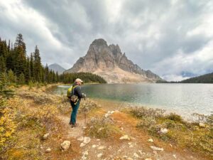 A hiker stands next to Cerulean Lake at Mount Assiniboine