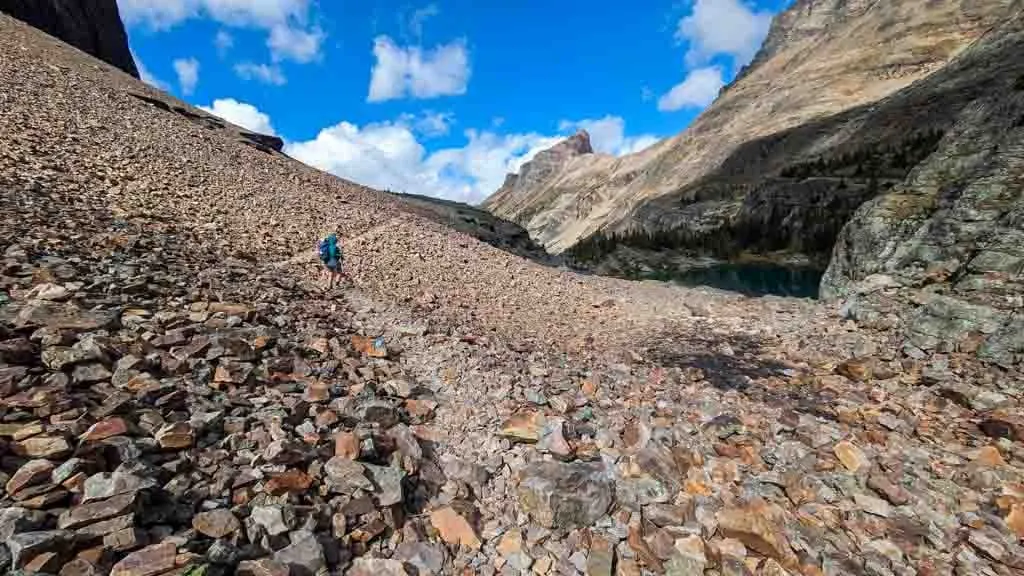 A hiker walks up a rocky slope near Lake Oesa in Yoho National Park