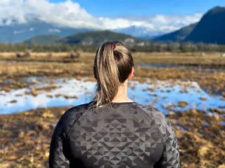 A woman wears a Merino wool shirt on a hike. Is Merino wool worth it?