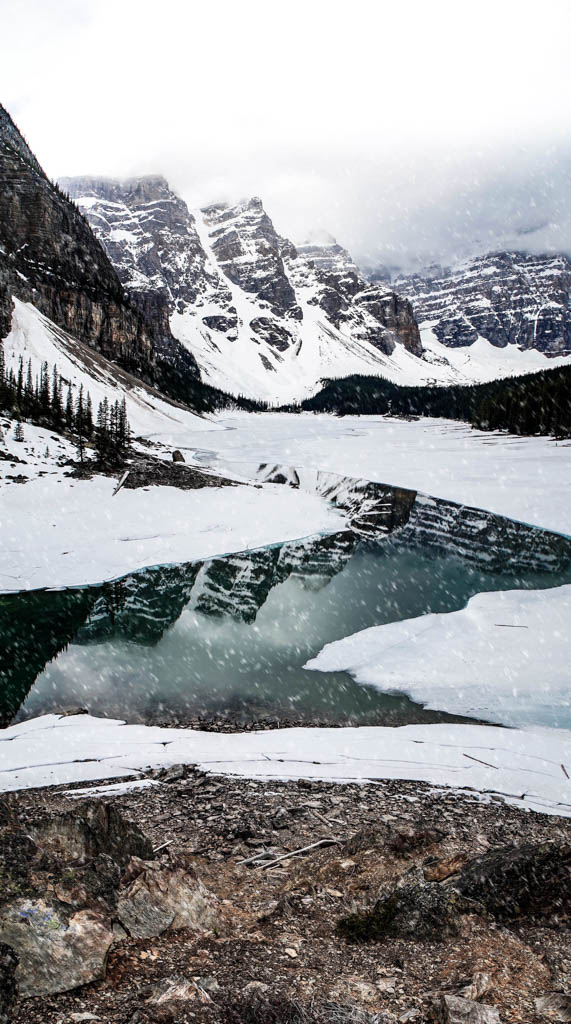 Moraine Lake in May with ice on the lake and snowy mountains. 