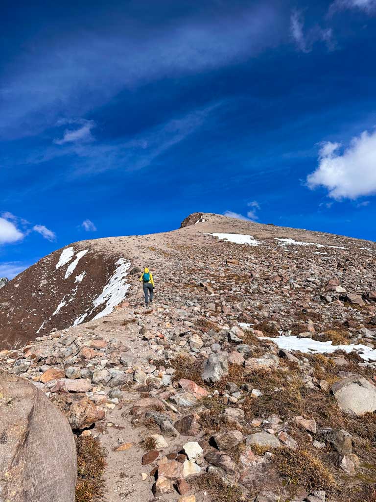 A hiker walks up a steep rocky slope to Diamond Head Peak in Garibaldi Provincial Park
