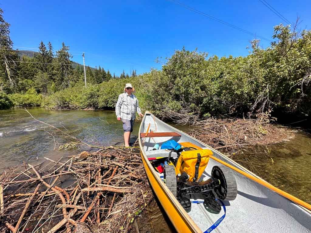 A prepares to lift a canoe over a beaver dam in Whistler