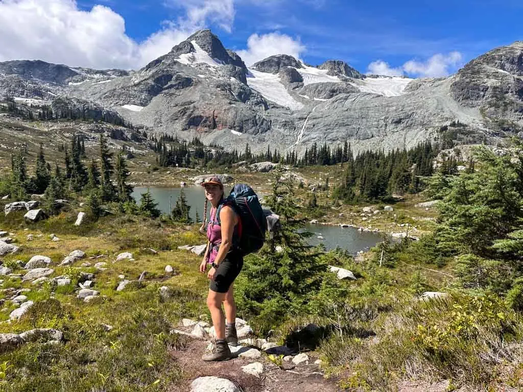 A hiker in front of alpine lakes and glaciers at Semaphore Lakes in Pemberton, BC