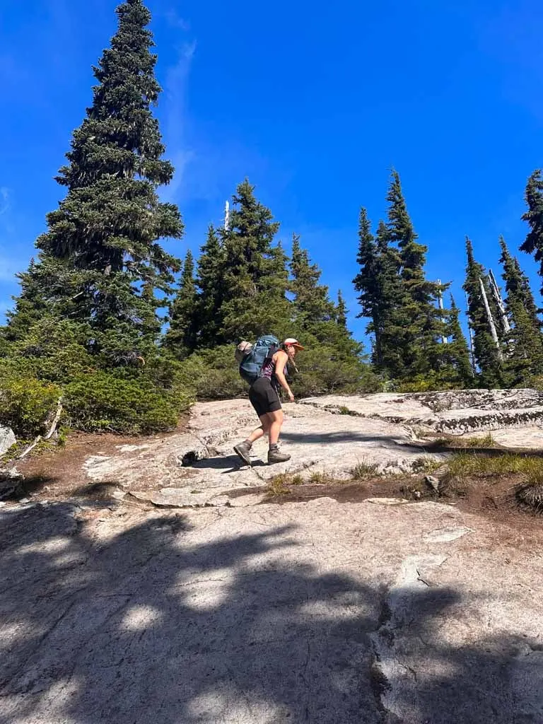 A hiker walks up a rock slab on the way to Semaphore Lakes