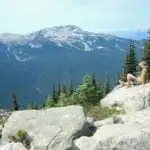 A hiker sits on a rock and enjoys the view on the Blackcomb trails