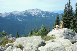 A hiker sits on a rock and enjoys the view on the Blackcomb trails