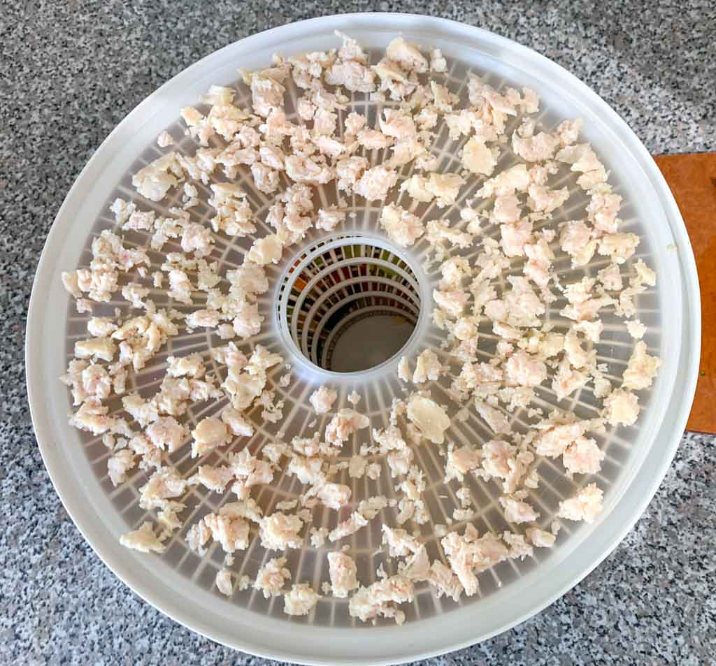 Chunks of canned chicken on a dehydrator tray. 