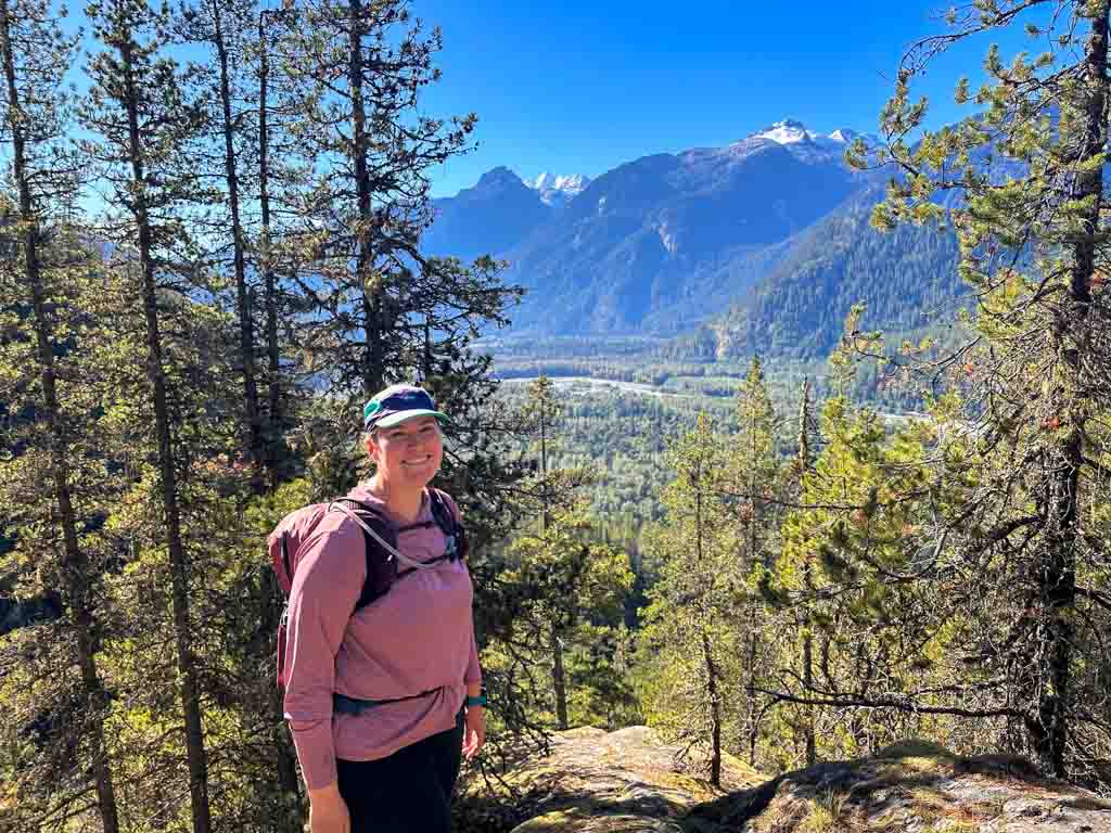 A woman poses in front a view in the Squamish River Valley