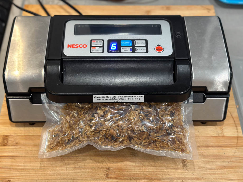 A vacuum-sealer in the middle of sealing a bag of dehydrated mushroom risotto for backpacking