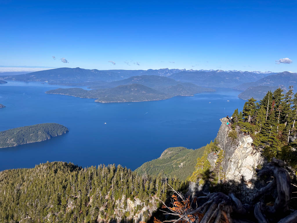 View of Howe Sound, islands, and people on a nearby cliff from St. Mark's Summit