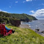 Two hikers sit on red chairs on the Green Gardens Trail in Gros Morne National Park, one of the best hikes in Newfoundland