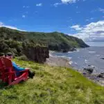 Two hikers sit on red chairs on the Green Gardens Trail in Gros Morne National Park, one of the best hikes in Newfoundland