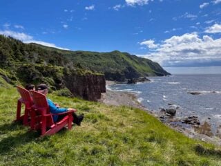 Two hikers sit on red chairs on the Green Gardens Trail in Gros Morne National Park, one of the best hikes in Newfoundland