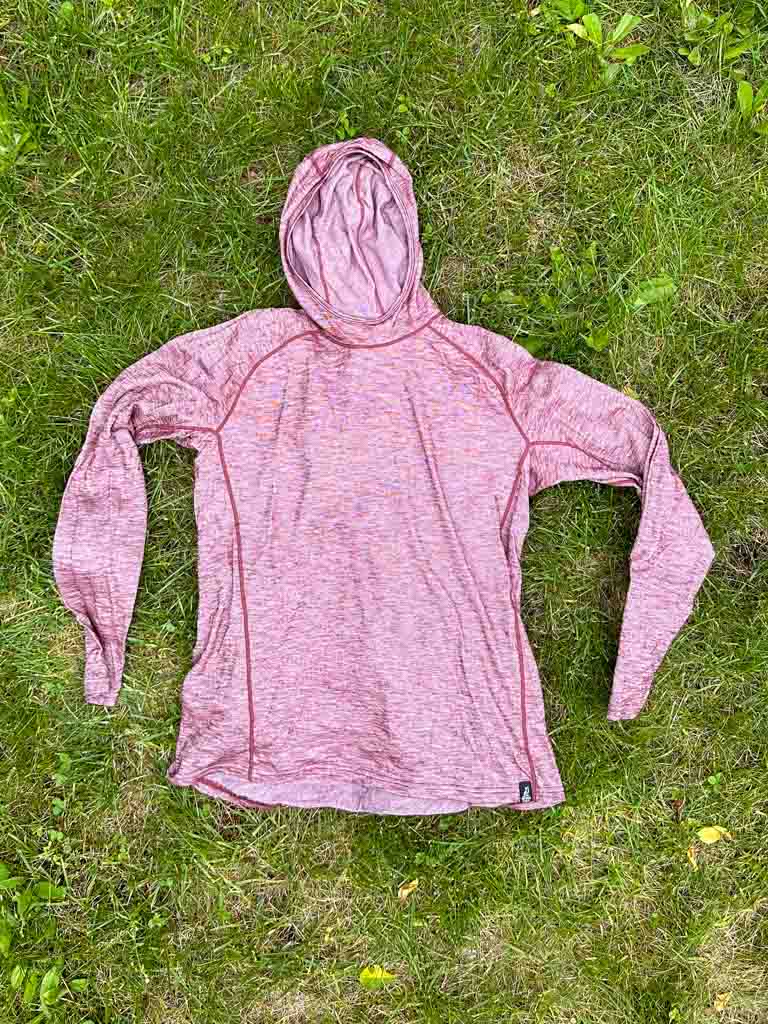 The Outdoor Vitals Tern Ultralight Merino Wool Sun hoodie lying flat on grass