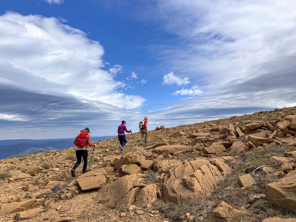 Three people hike off trail on the Tablelands in Gros Morne National Park in Newfoundland
