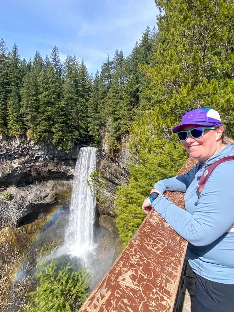 A hiker poses at Brandywine Falls near Whistler wearing the Black Diamond Alpenglow Pro sun hoodie