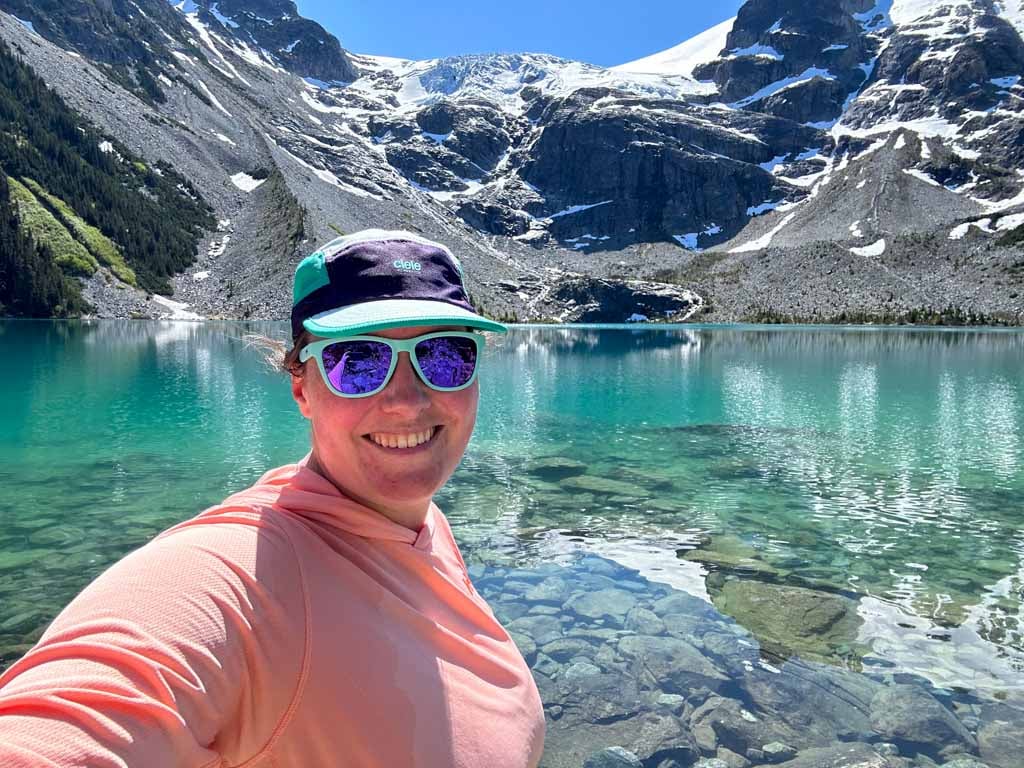 A hiker wearing the Helly Hansen Solen Sun Hoodie takes a selfie at Joffre Lakes
