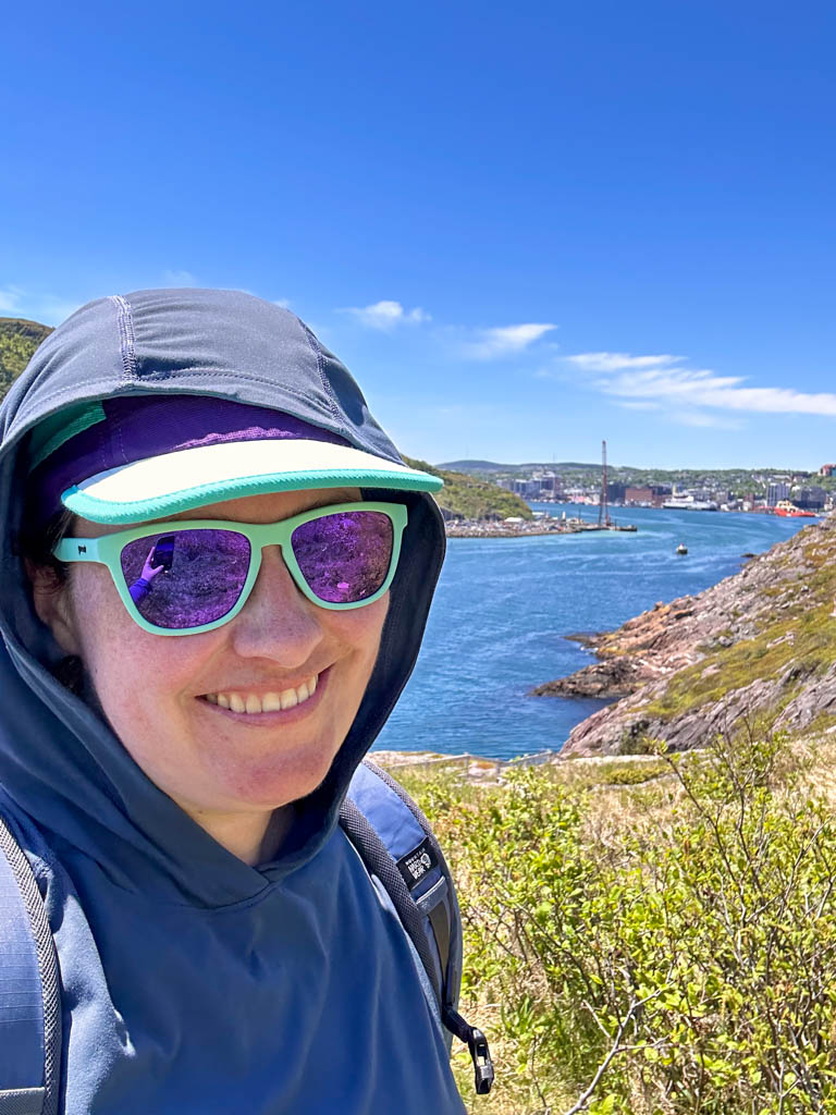 A hiker takes a selfie wearing the Mountain Hardwear Crater Lake Sun Hoodie in St. John's, Newfoundland