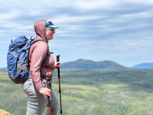 A woman wears the Outdoor Vitals Tern Sun Hoodie on a hike in the Tablelands in Newfoundland