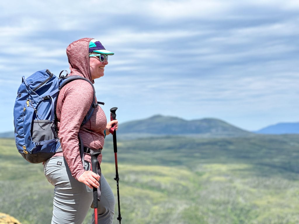 A woman wears the Outdoor Vitals Tern Sun Hoodie on a hike in the Tablelands in Newfoundland