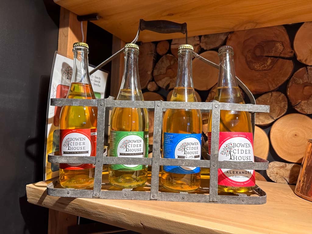 Bottles of cider on display on a wooden shelf at Bowen Cider House