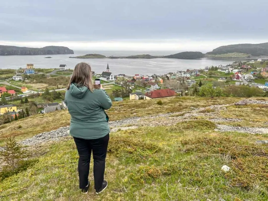 A woman takes a photo from the top of Gun Hill in Trinity, Newfoundland