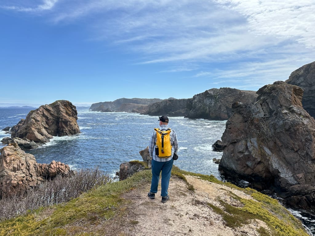 A hiker poses at a viewpoint on the Spiller's Cove Trail in Twillingate, NL