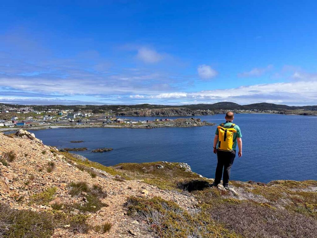 A man stands on a hillside near Smith's Lookout looking down on Twillingate