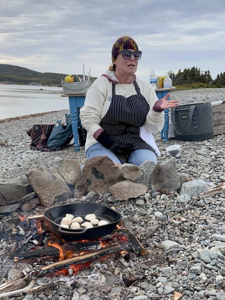 Chef Crystal from Wild Island Kitchen prepares scallops over the fire on a beach boil up