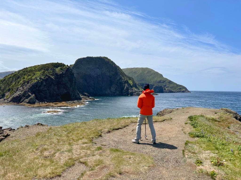 A hiker stands on a bluff in Bottle Cove