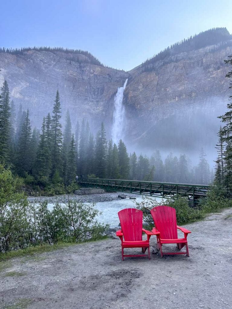 Morning mist on Takakkaw Falls with the Parks Canada red chairs in the foreground.