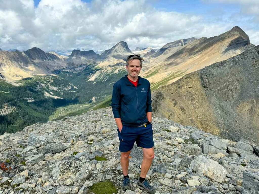 A hiker stands on the summit of Paget Peak