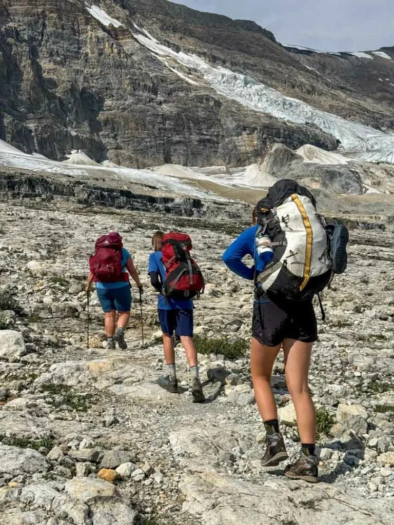 Hikers on the Iceline Trail walk below glaciers.