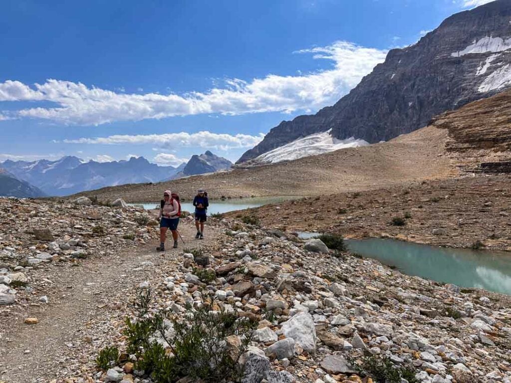 Hikers walk next to turquoise lakes on the Iceline Trail