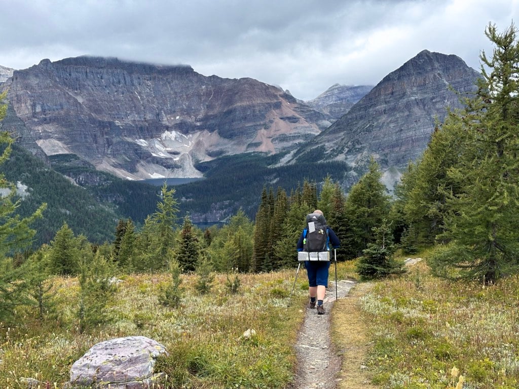 A hiker walks through Healy Pass with Egypt Lake and Scarab Lake visible across the valley