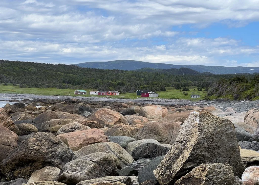 Rocks on the beach and fishing shacks at Lobster Cove Head